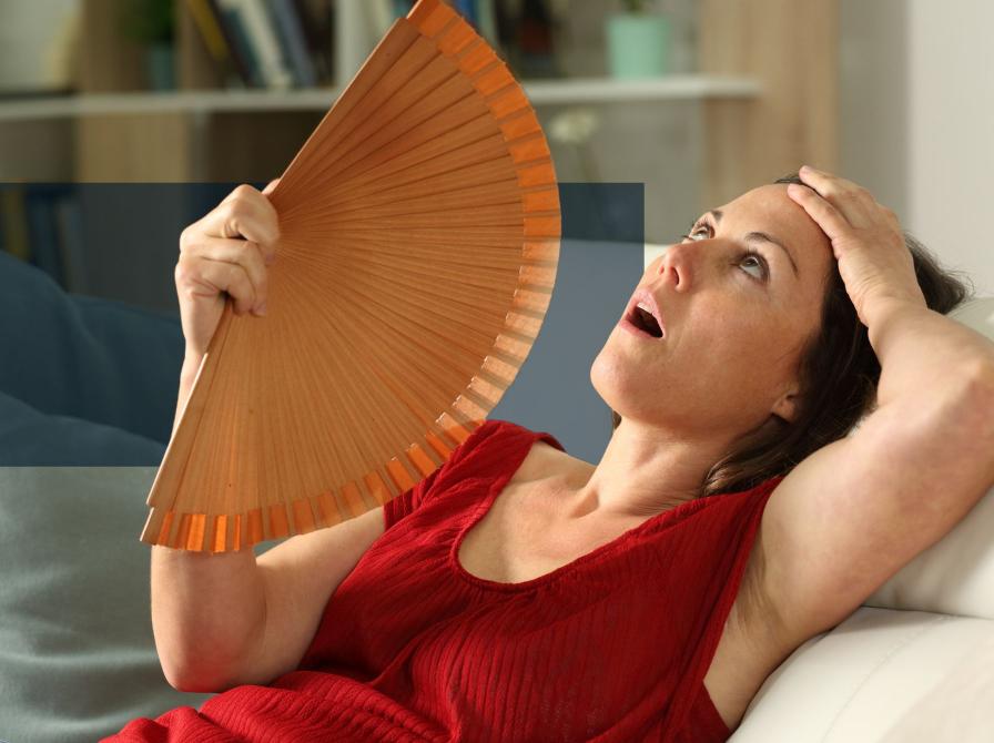 Kvinde, der sidder i en sofa og vifter sig med en håndvifte.